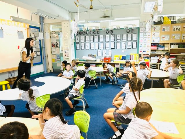 a woman talking to children in a classroom