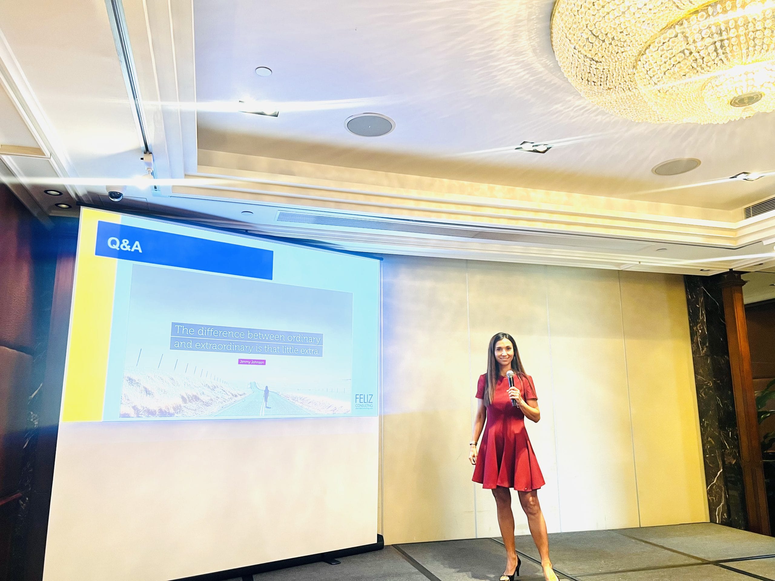 Woman in red delivering a presentation on stage