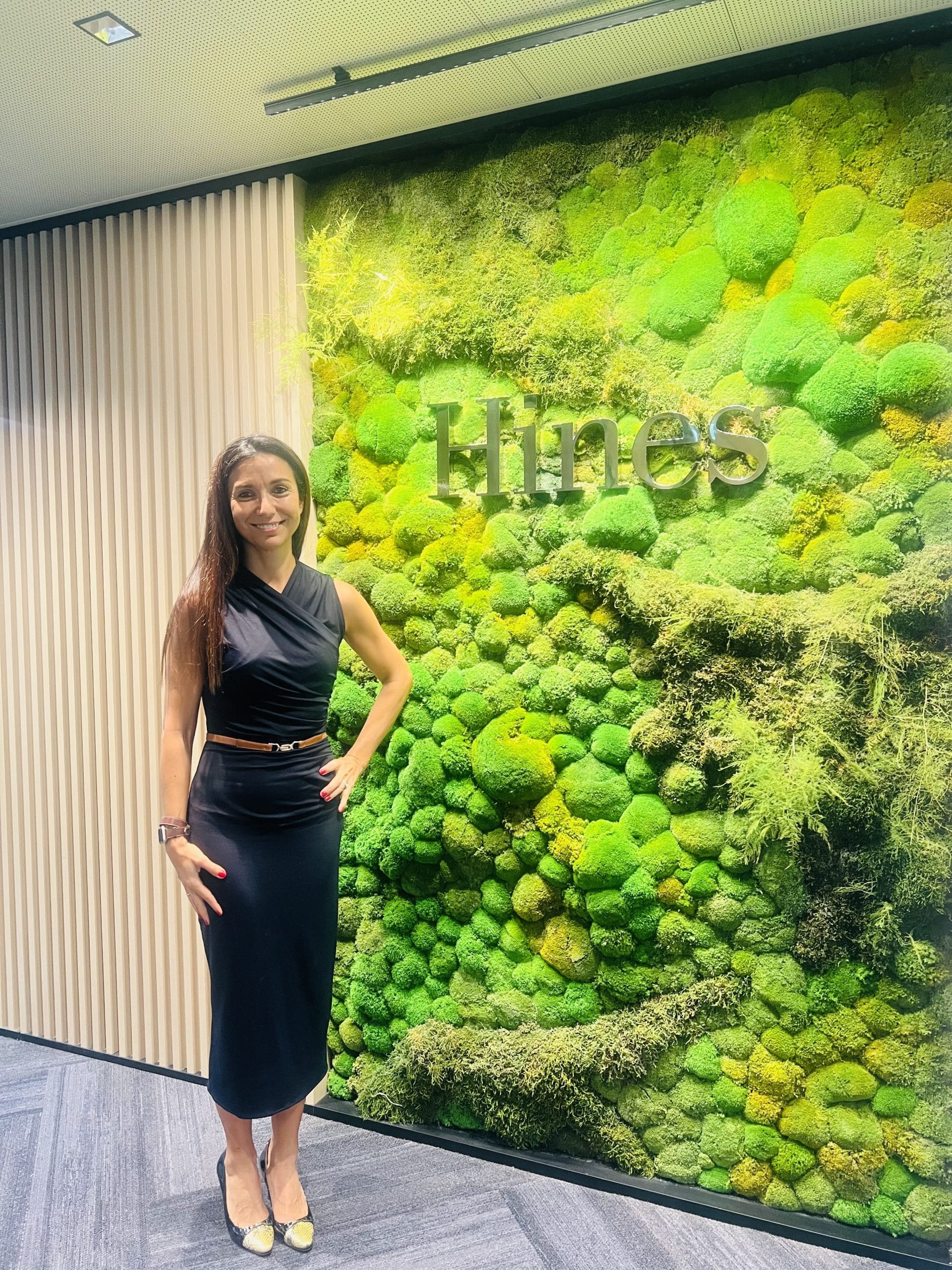 Woman in a black dress in front of the Hines official wall sign